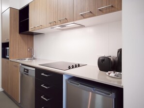 Eine moderne Küche mit Holzausstattung, einem Edelstahl-Geschirrspüler und einer Kaffeemaschine.