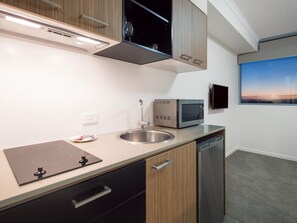 Une cuisine moderne dotée d’un four à micro-ondes encastré, d’un évier en acier inoxydable et d’une fenêtre offrant une vue sur le paysage urbain.