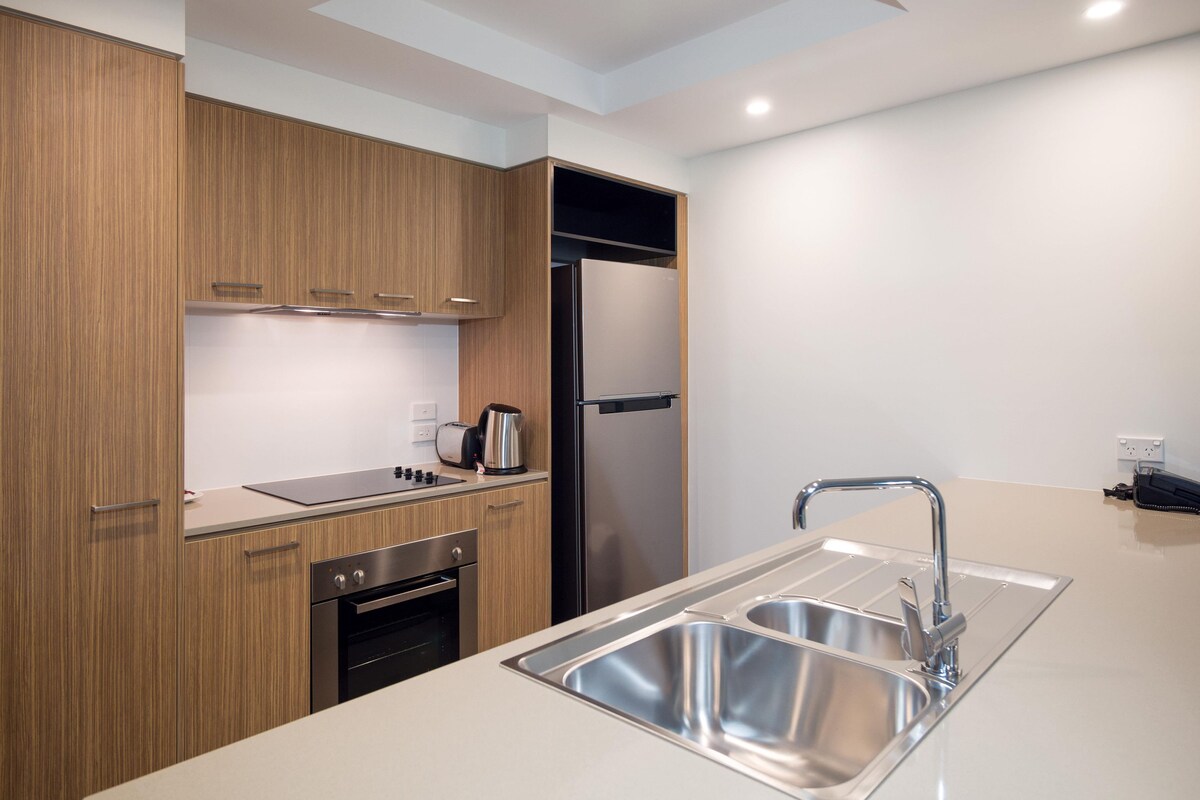 A modern kitchen with wooden cabinets, stainless steel appliances, and a double sink.