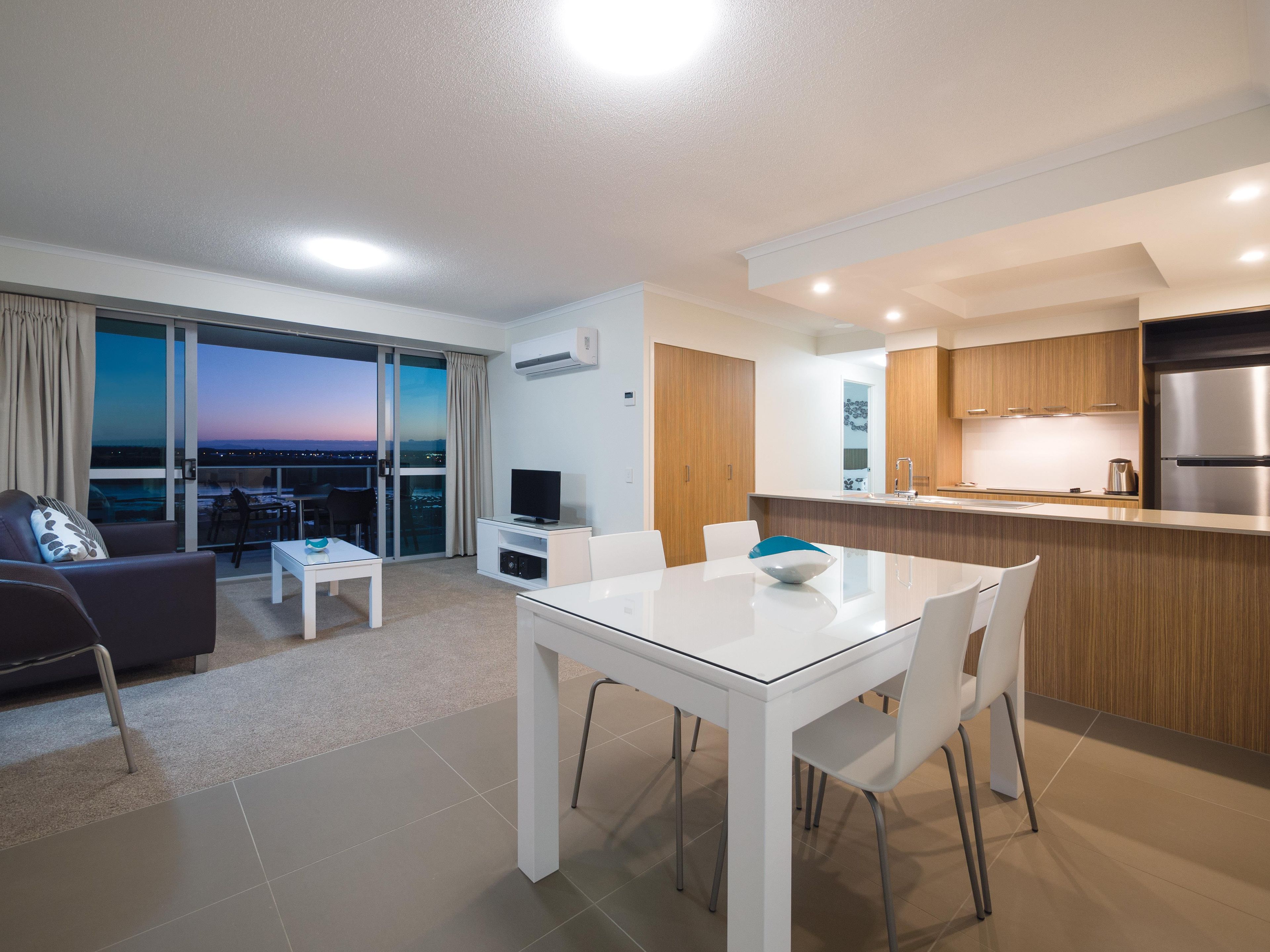 Un apartament modern amb zona de menjador, cuina i un balcó amb vista a la ciutat.