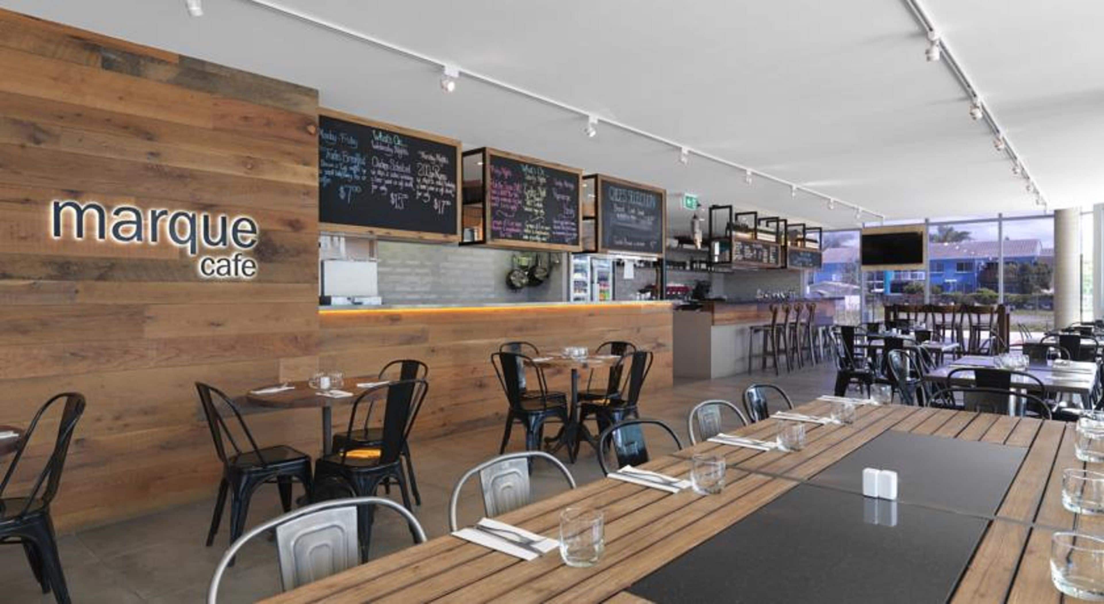 A cafe with wooden walls, blackboard menus, and tables with chairs.