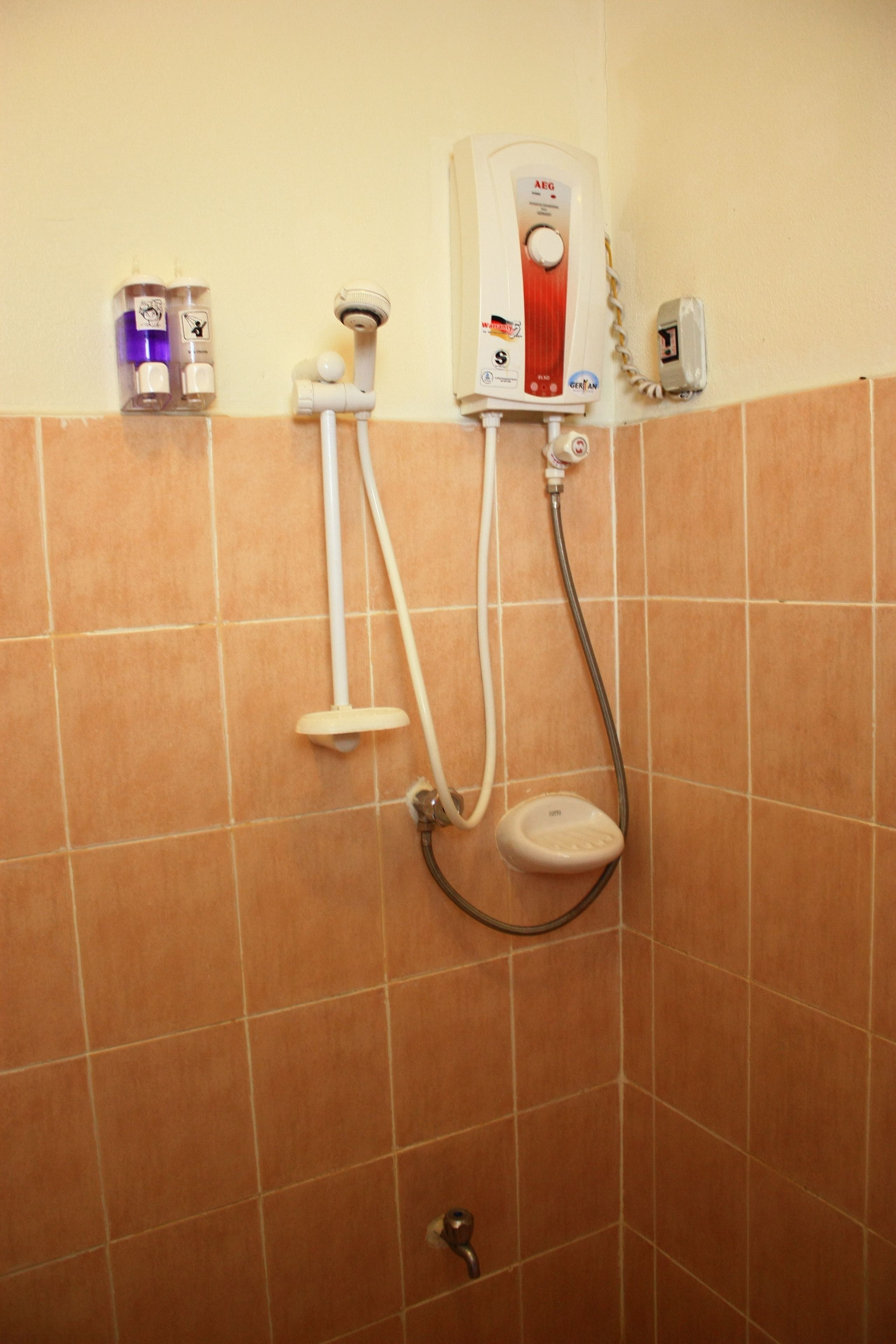A bathroom with a shower, a toilet, and a hand dryer.