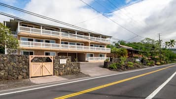 A two-story hotel with a stone wall entrance, a wooden gate, and a balcony on the second floor.