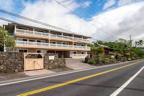 A two-story hotel with a stone wall entrance, a wooden gate, and a balcony on the second floor. - Kona Seaspray (Kailua-Kona)