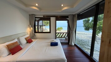 Una camera da letto con un letto grande, vista sulla spiaggia e un balcone con ringhiera in legno.