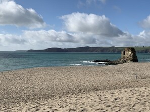 A pebbly beach with a prominent rock formation and distant hills. - Duke of Cornwall (St Austell)