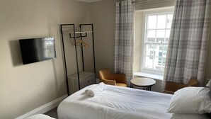 A hotel room with two beds, a TV mounted on the wall, a small table, and a chair.