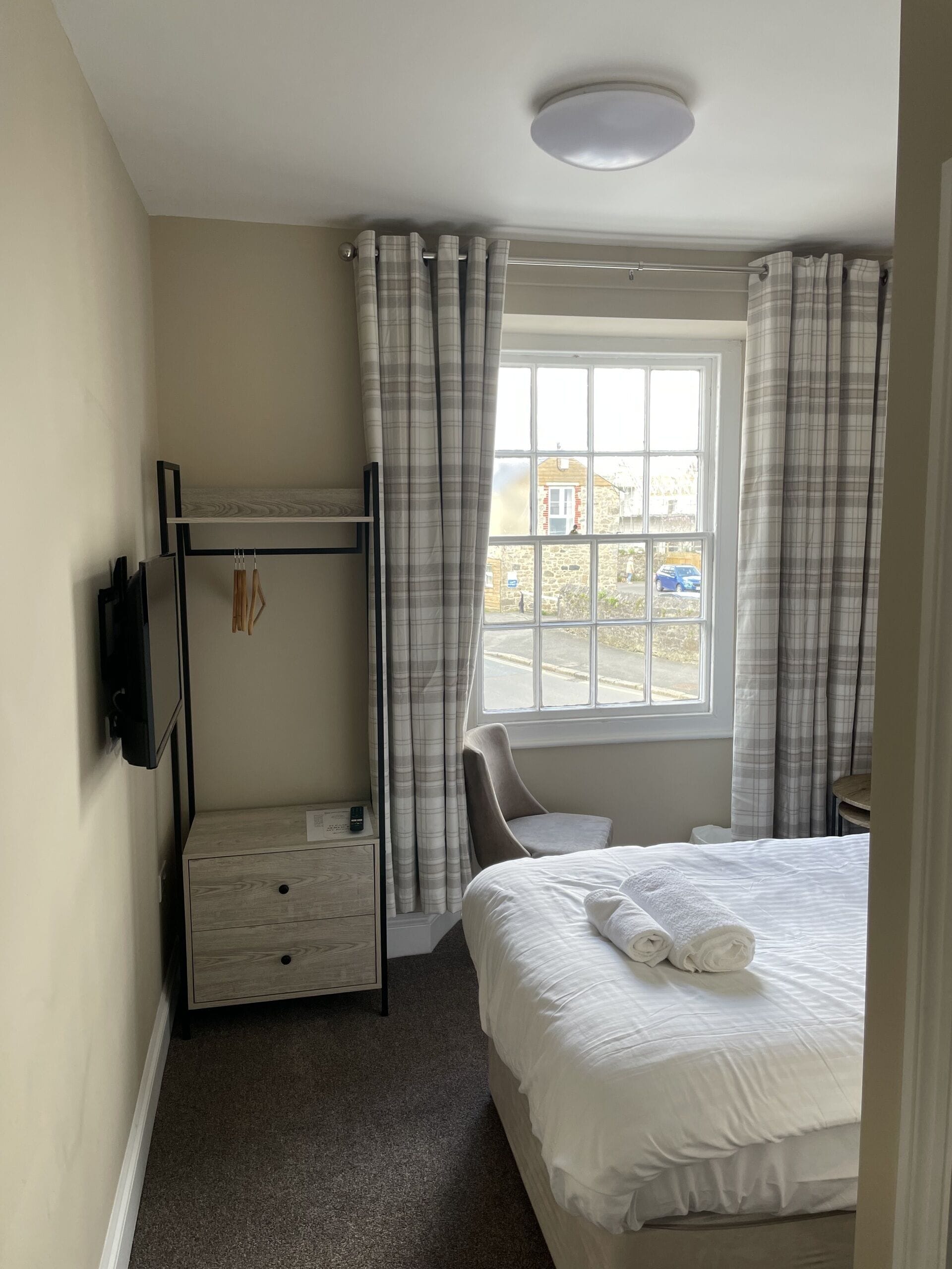 Hotelkamer met een stapelbed, een eenpersoonsbed, een klein bureau, een stoel en een raam met gordijnen.
