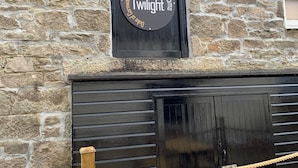A stone building with a sign reading "Escape Rooms Twilight" and a black garage door.