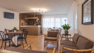 A dining area with a bar, wicker furniture, and a television mounted on the wall.