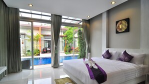A modern hotel room with a large bed, a view of an outdoor swimming pool, and a glass door leading to the pool area.