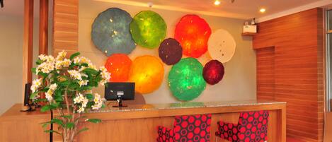 A reception area with a wooden reception desk, a potted plant, and colorful wall decorations.