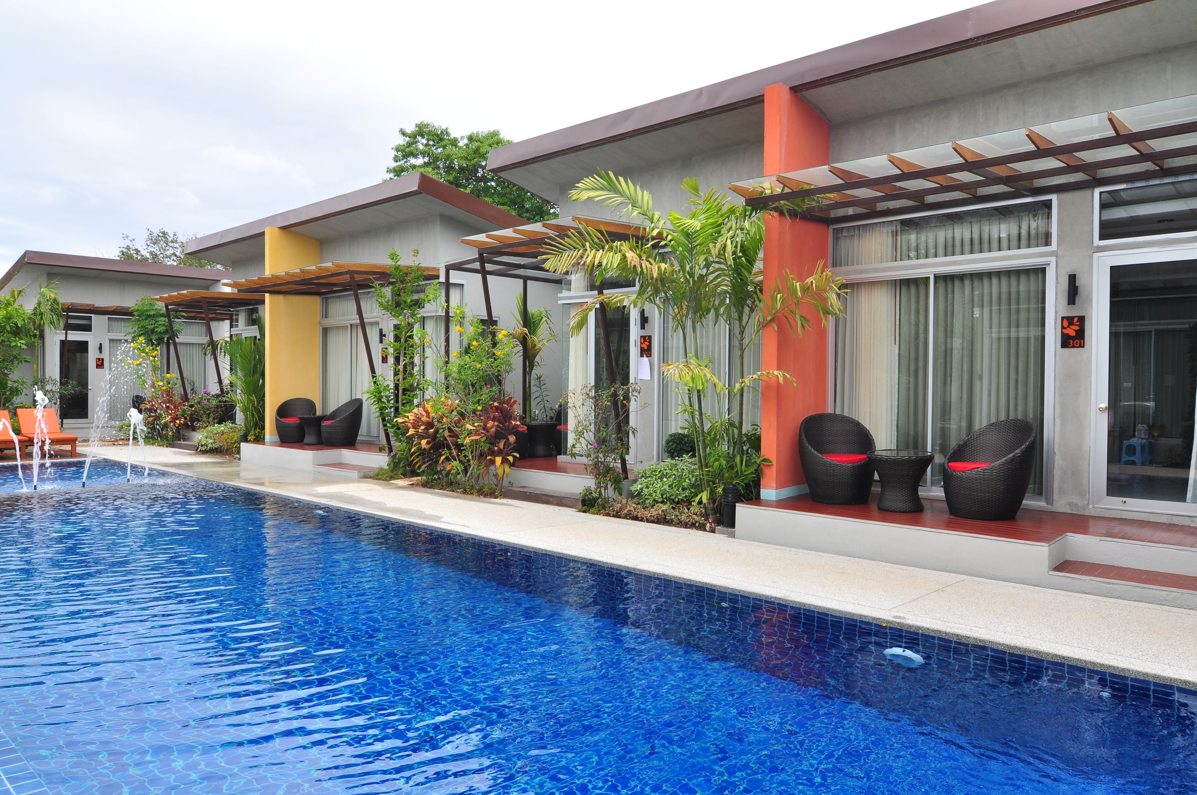 A modern hotel with a swimming pool, outdoor seating, and lush landscaping.