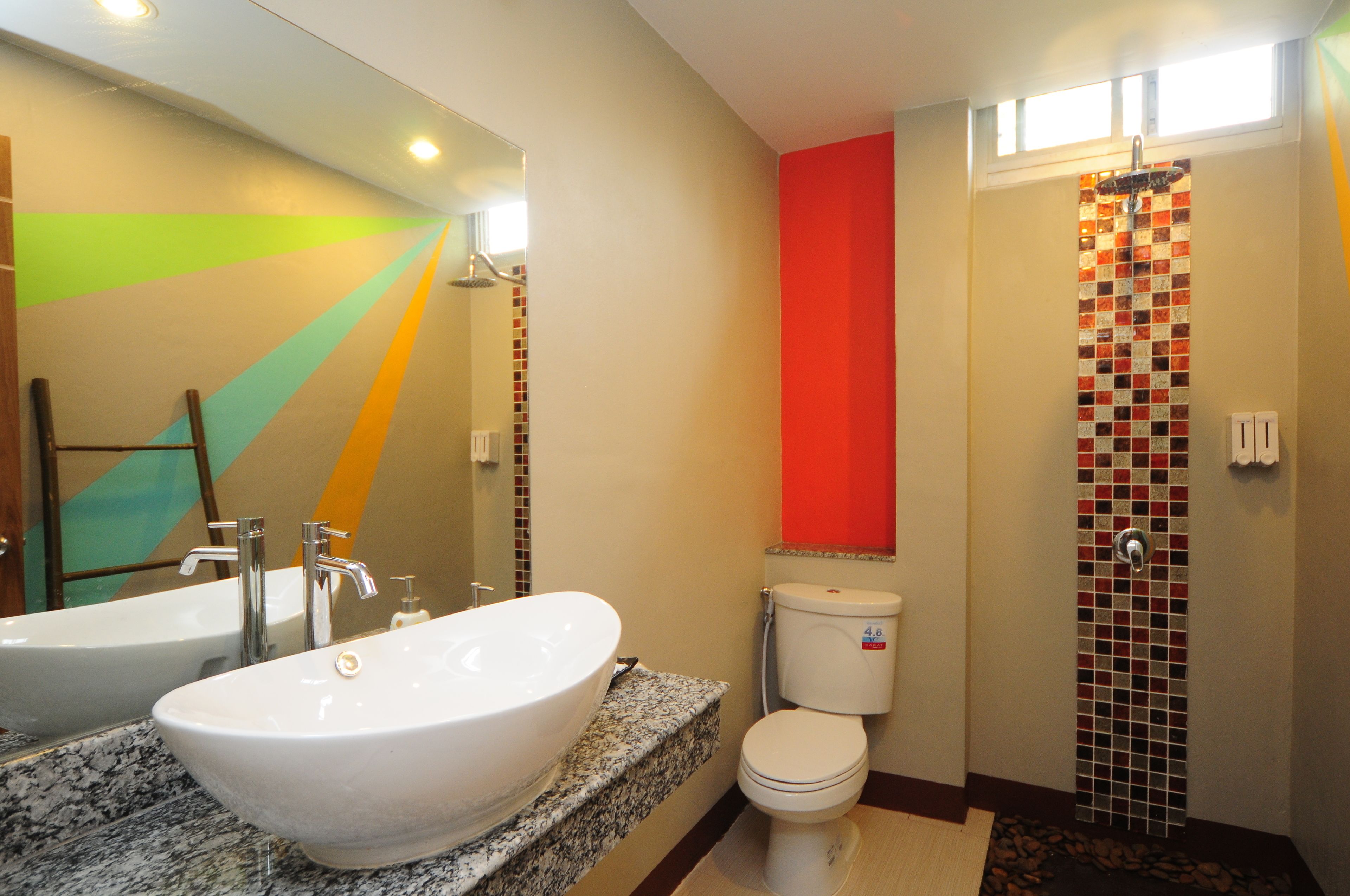 Un baño con un lavamanos grande de color blanco, un inodoro y una zona de ducha.