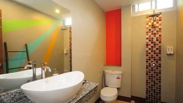 Un baño con un lavamanos grande de color blanco, un inodoro y una zona de ducha.