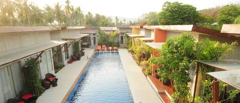 Zona de piscina con sillones de descanso y plantas en macetas.
