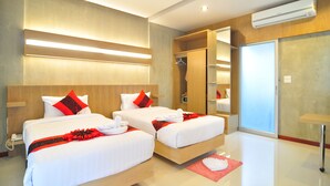 A hotel room with two beds, a wooden headboard, a large mirror, and an air conditioning unit.