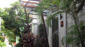 A covered garden area with a stone pathway, various plants, and a glass door with a number sign.