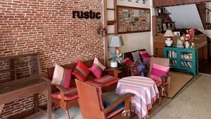 A rustic room with a brick wall, wooden furniture, and a loft area with a staircase. - Rustic Guesthouse (Chiang Mai)