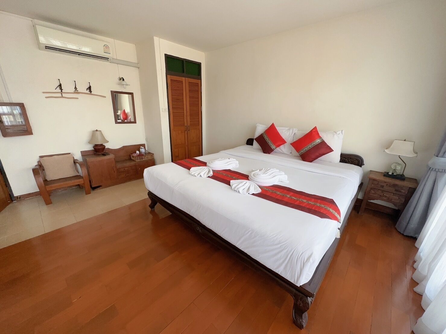 Een netjes ingerichte hotelkamer met een groot bed, houten meubels, een bureau en een kledingkast.