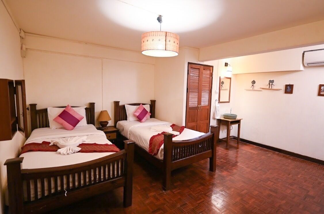 A room with two wooden beds, a small table, and a ceiling light fixture.
