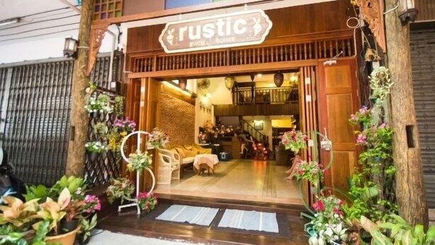 A rustic-themed restaurant with a wooden facade, indoor seating, and a variety of potted plants outside. - Rustic Guesthouse (Chiang Mai)