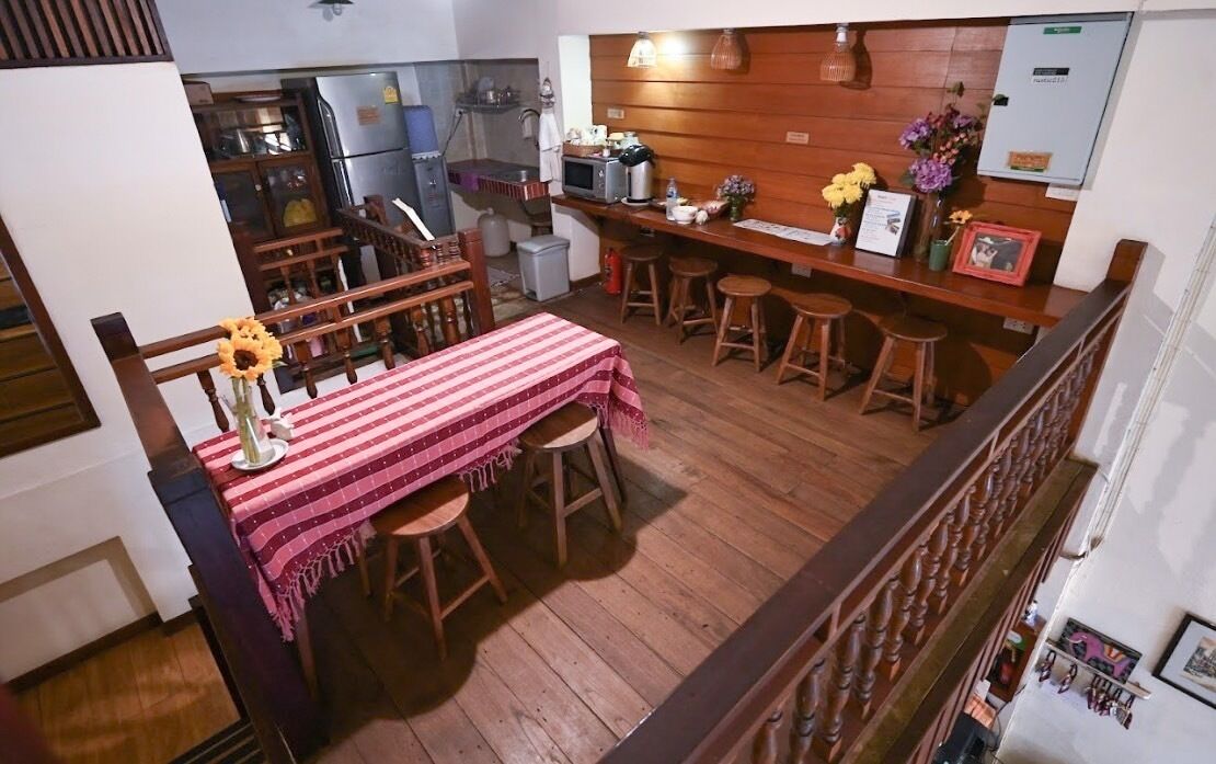 A dining area with a wooden table and chairs, a kitchen in the background, and a small bar area with stools.