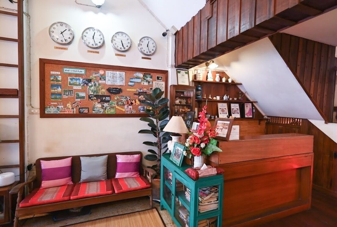 Ein gemütliches Zimmer mit einem Holzbüro, einer Pinwand mit verschiedenen Aushängen, einer Couch mit Kissen und einer Uhr an der Wand.