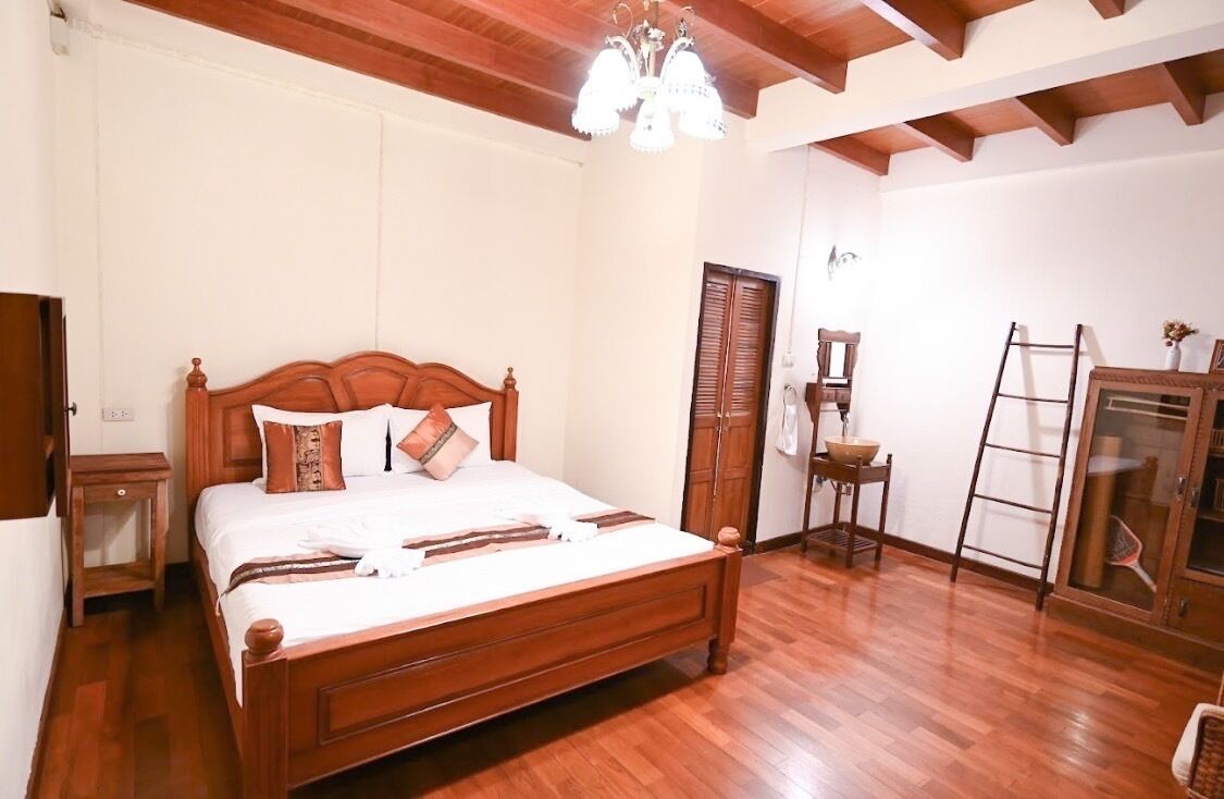 A bedroom with a wooden bed, a chandelier, a wardrobe, and a ladder.