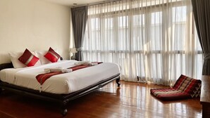 A hotel room with a large bed, a wooden floor, and a view through sheer curtains. - Rustic Guesthouse (Chiang Mai)
