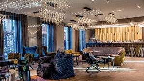 A modern hotel lobby with a mix of seating areas, a bar, and large windows offering city views. - Motel One Berlin-Potsdamer Platz (Berlin)