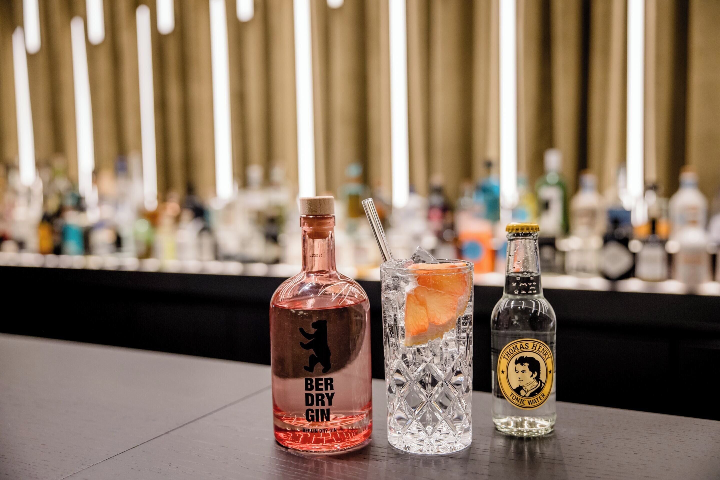 A bar setting with bottles of 'BER DRY GIN' and 'THOMAS HENRY Tonic Water' on a counter.