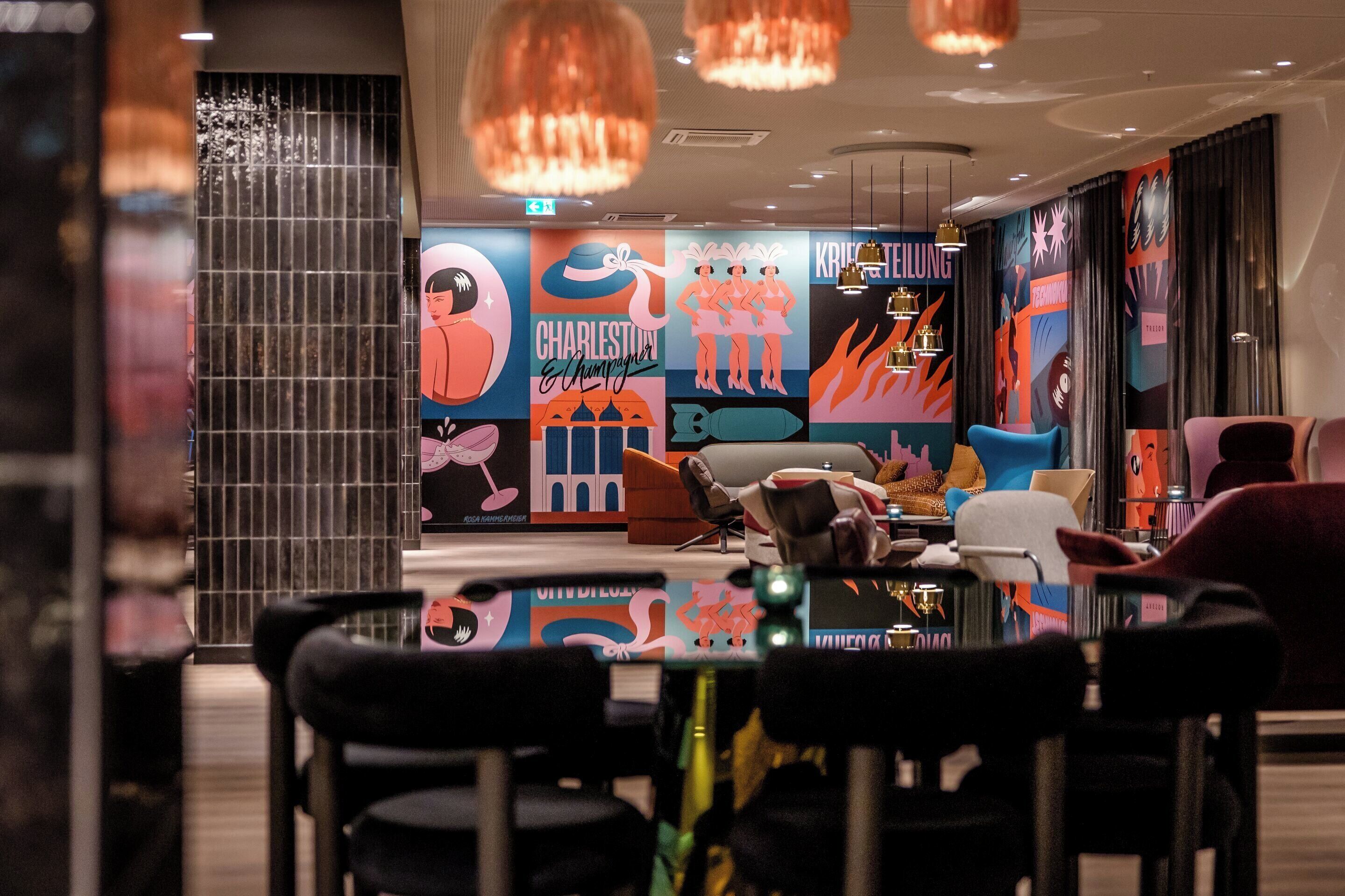 A modern dining area with a central table, black chairs, and colorful wall art.