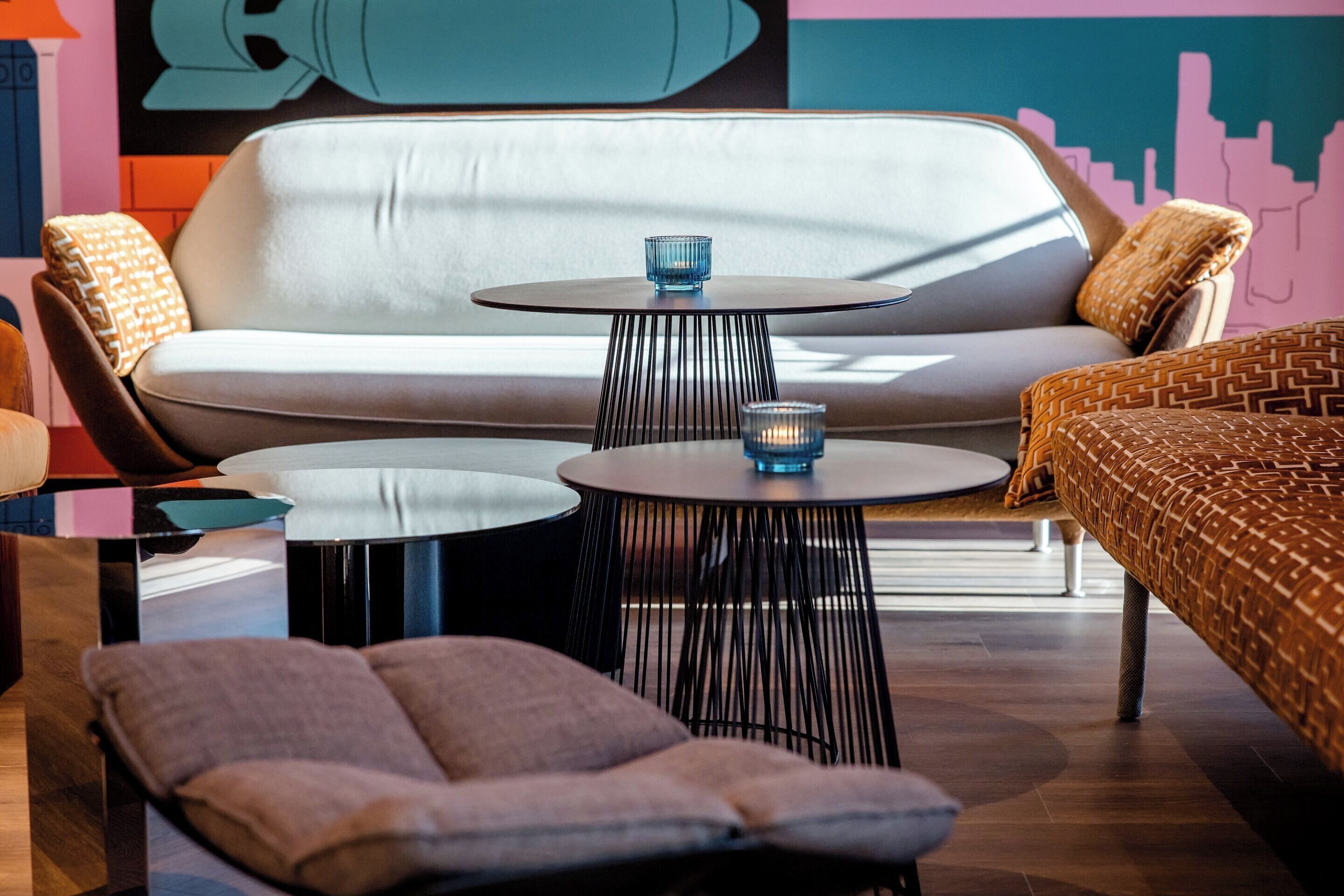 Ein stilvoller Lounge-Bereich mit einer Couch, zwei runden Tischen und einem Sessel.