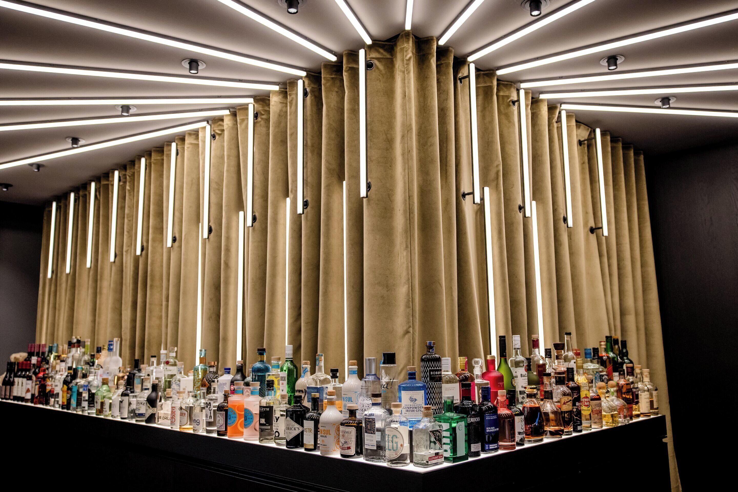 A bar area with a variety of liquor bottles and a curtain backdrop.