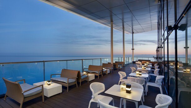 Una terraza con asientos y mesas, con vistas al mar.