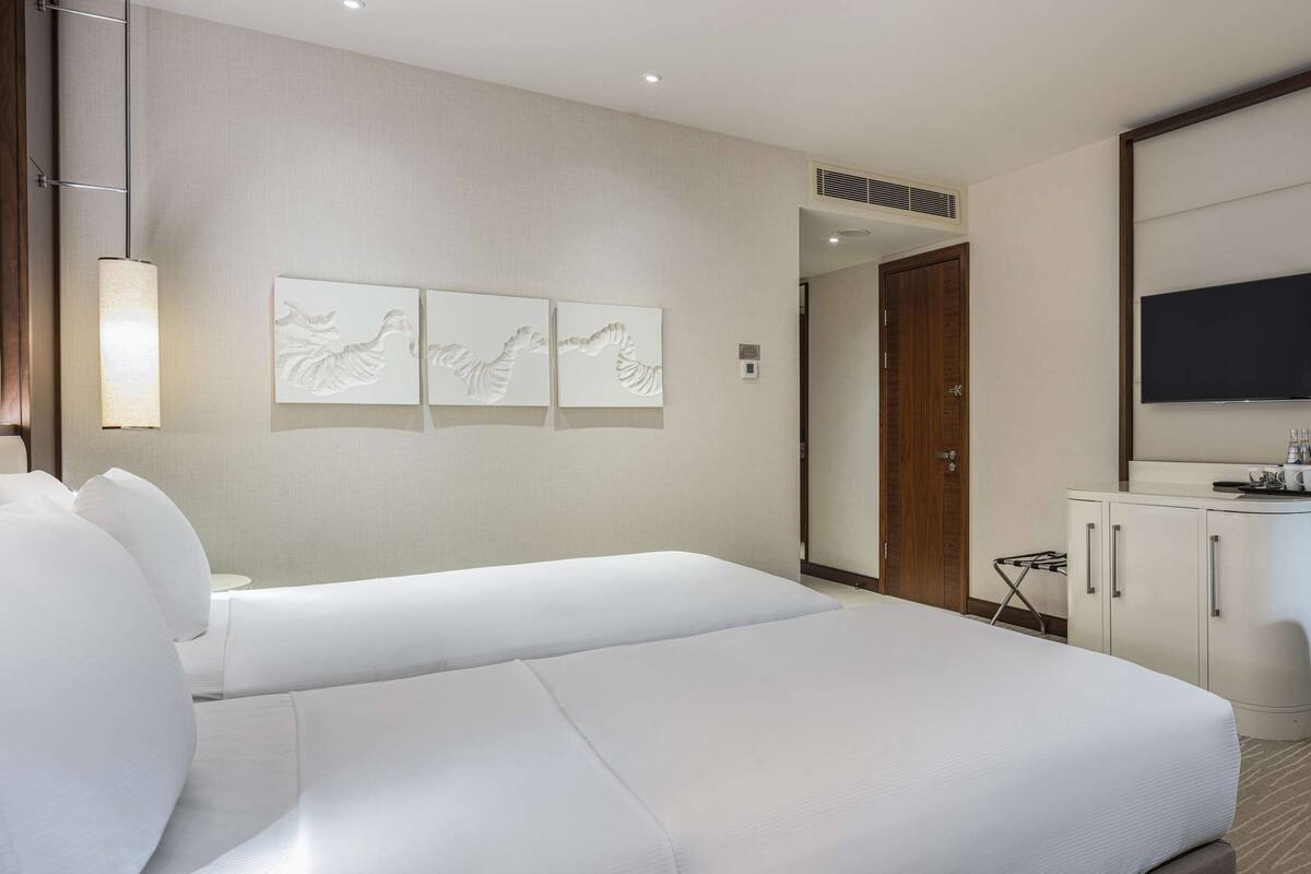 A hotel room with a large bed, a desk with a chair, a television, and a mirror.