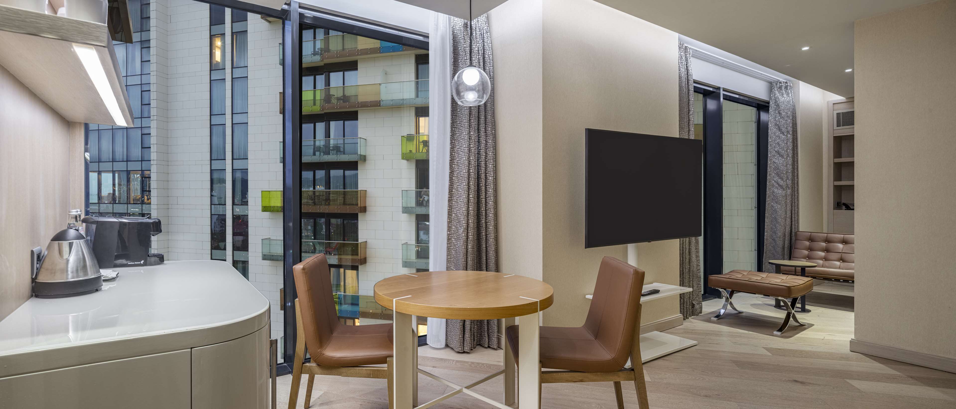Ein modernes Hotelzimmer mit Essbereich, Flachbildfernseher und einer Couch.