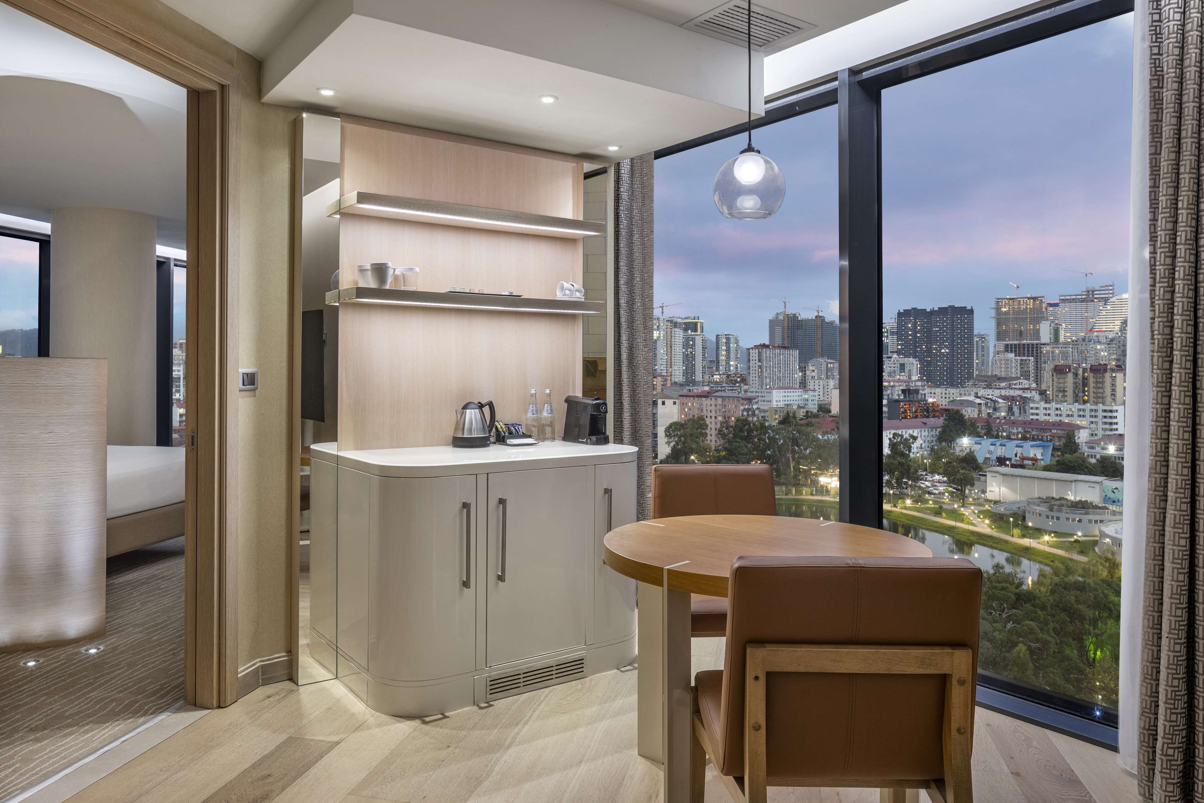 Una cocina moderna con vista a la ciudad, un comedor con mesa y sillas, y un ventanal grande.