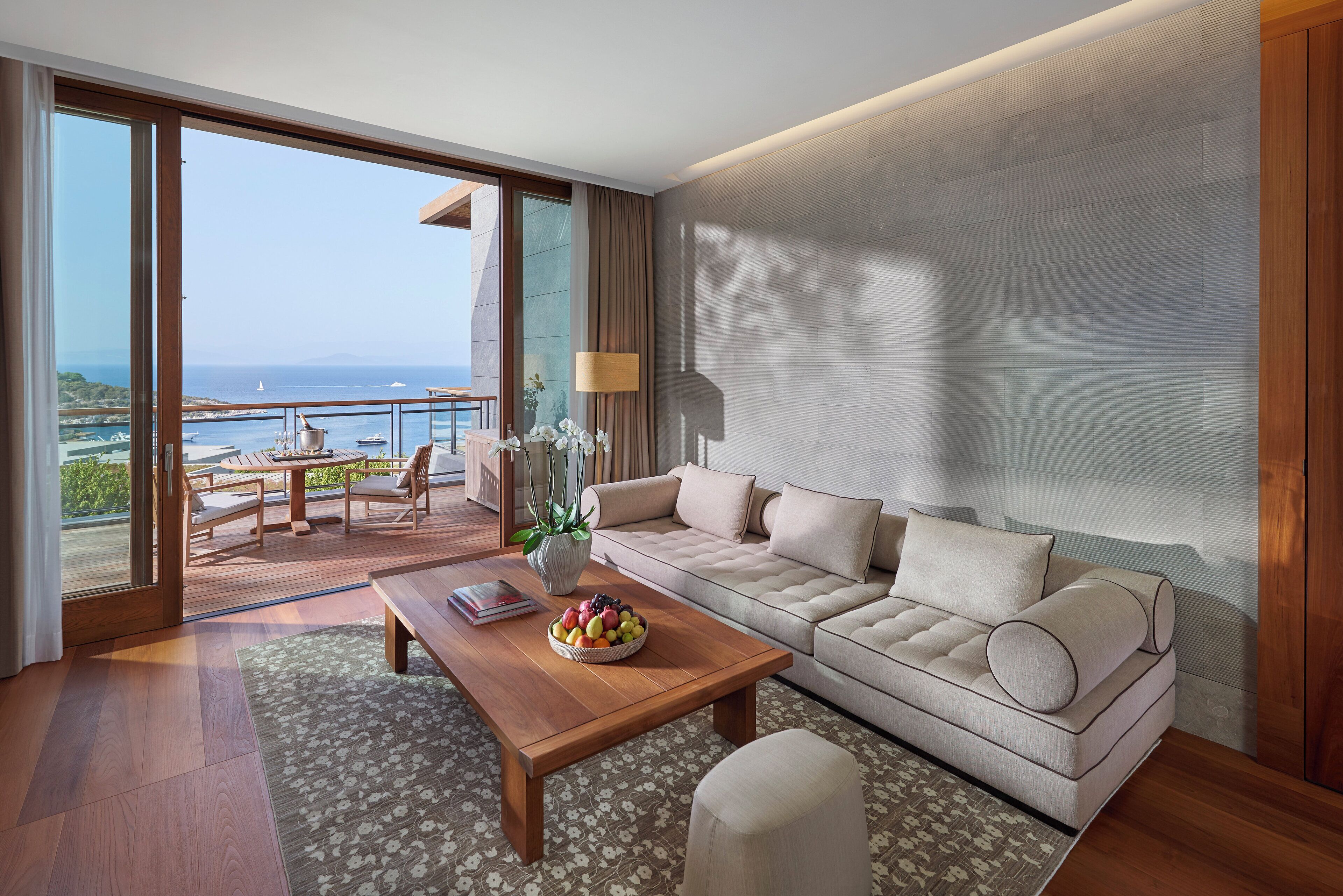 A modern living room with a sofa, coffee table, and a view of the sea.