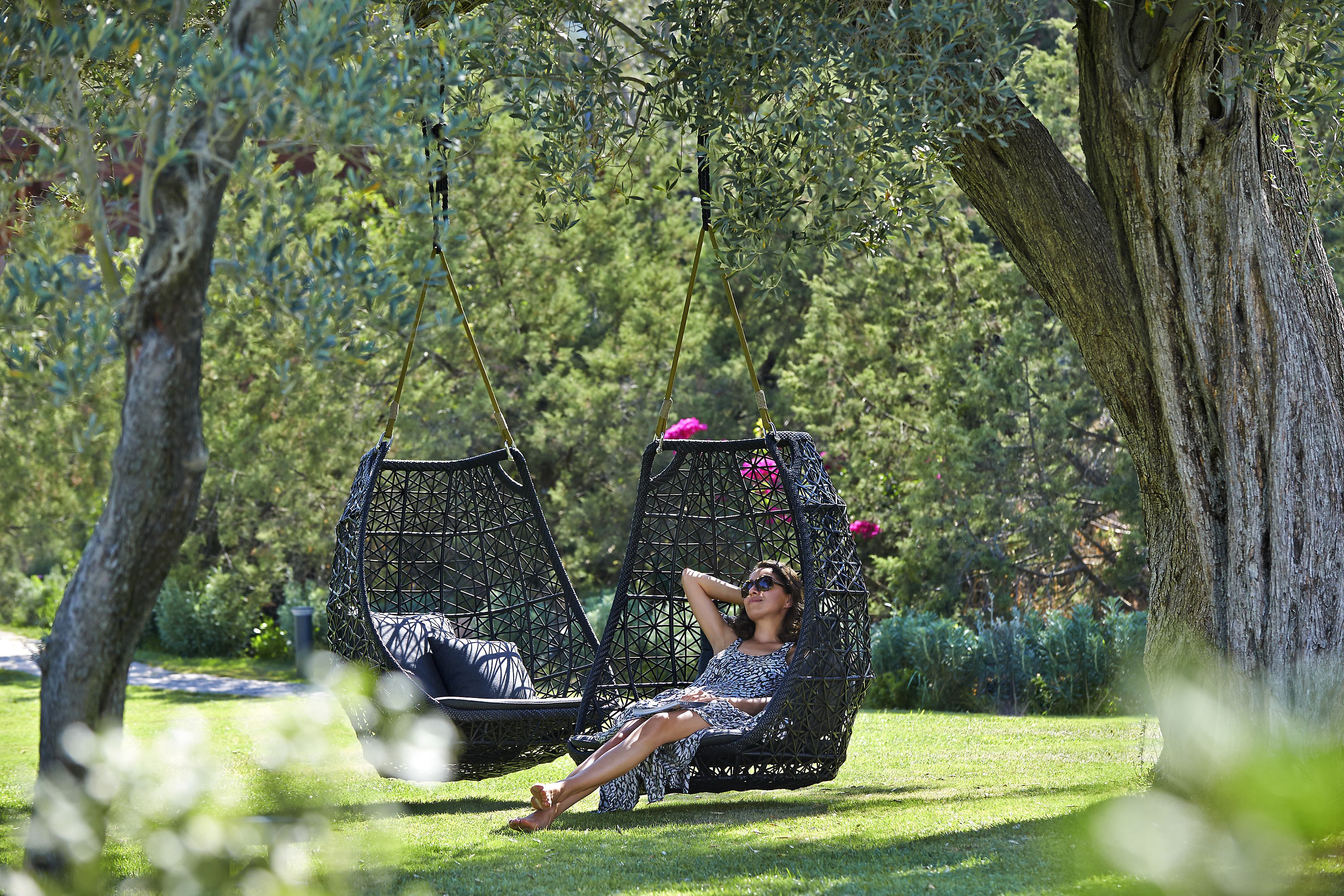 A person relaxing on a hammock swing in a lush garden setting.