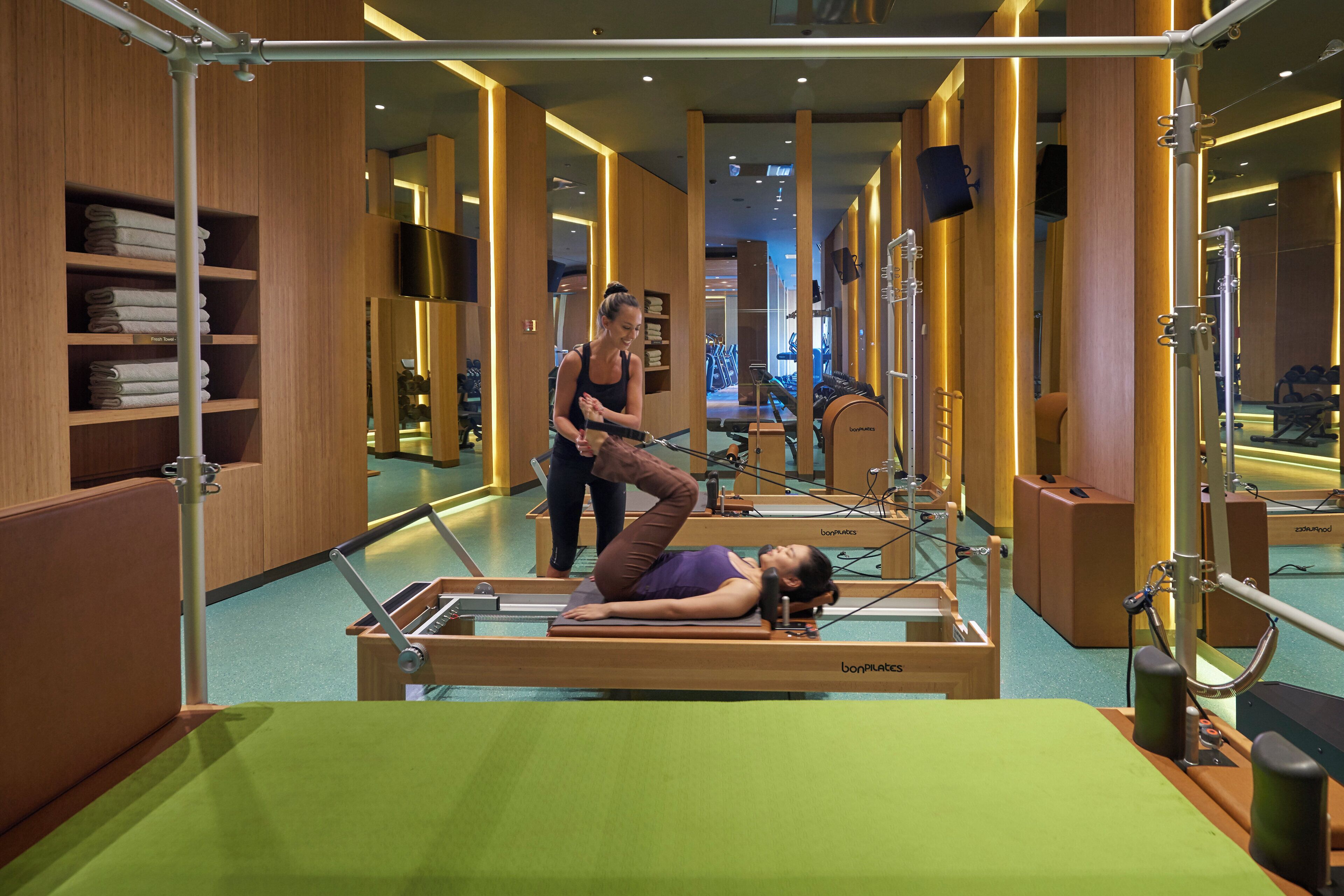Un studio de Pilates équipé de matériel, doté d’un miroir et dont les murs sont en bois.