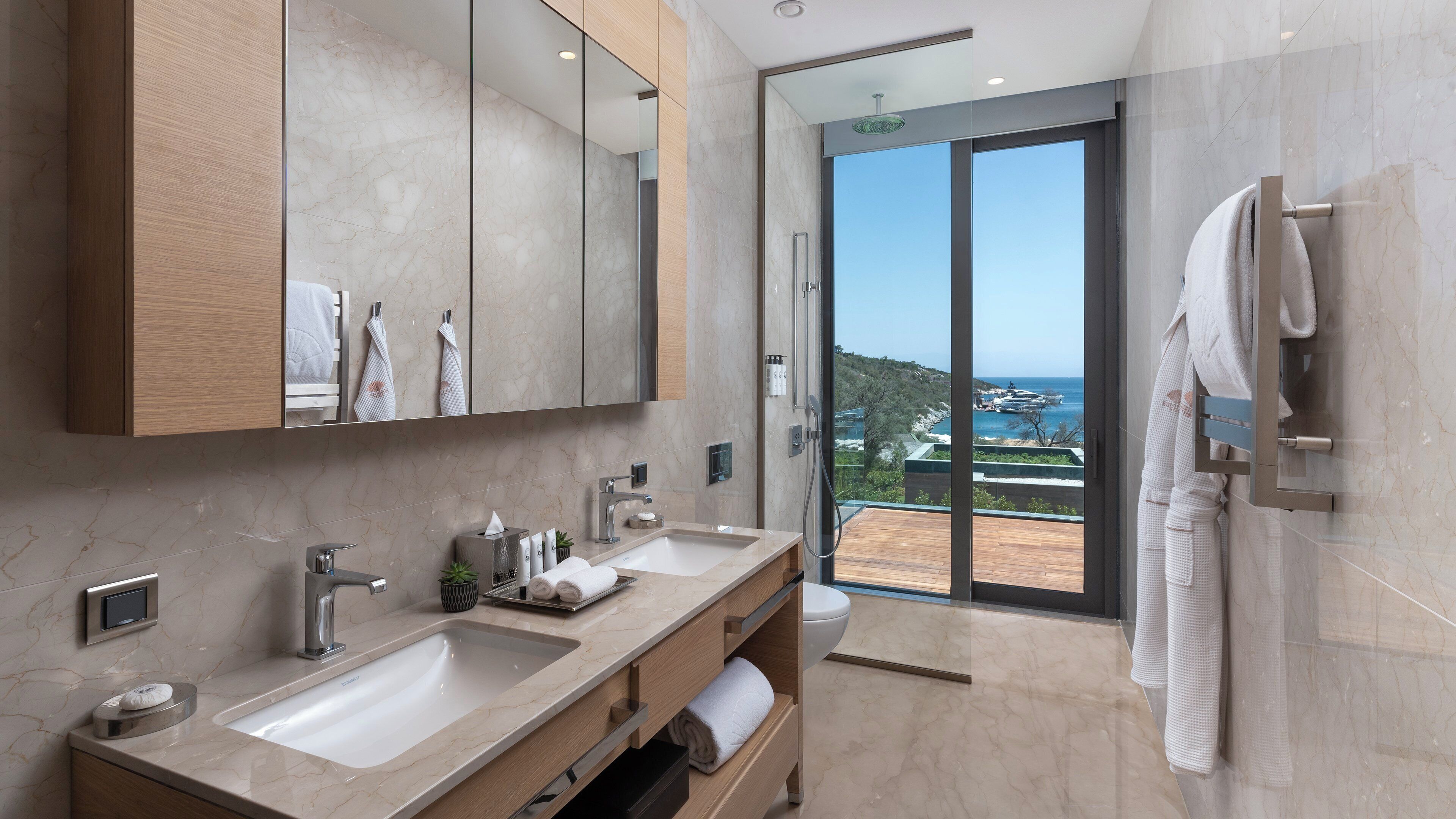 Une salle de bain moderne avec deux lavabos, un grand miroir et une vue sur la mer.