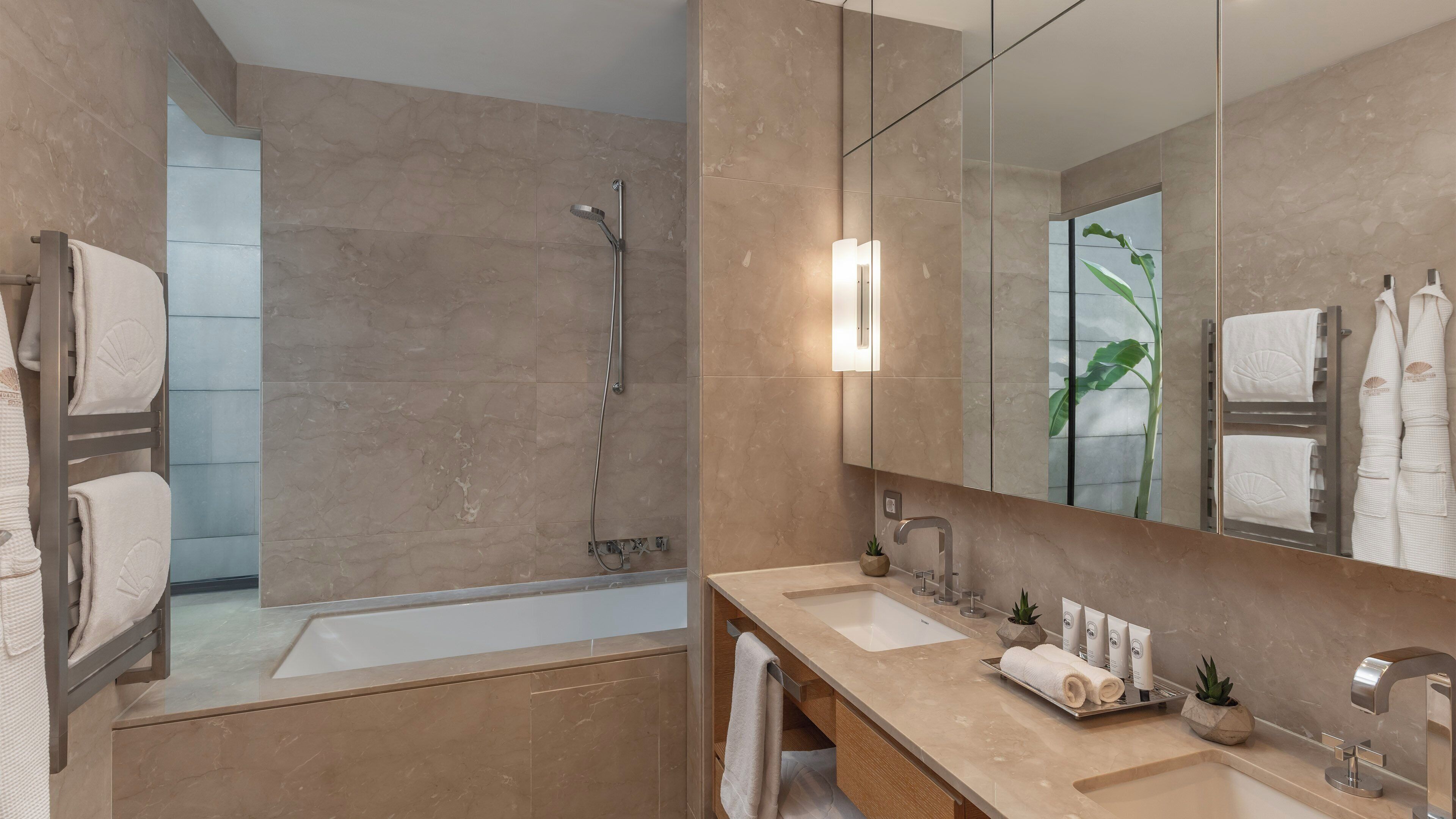 Un baño moderno con bañera, ducha, tocador con lavabo y un espejo grande.