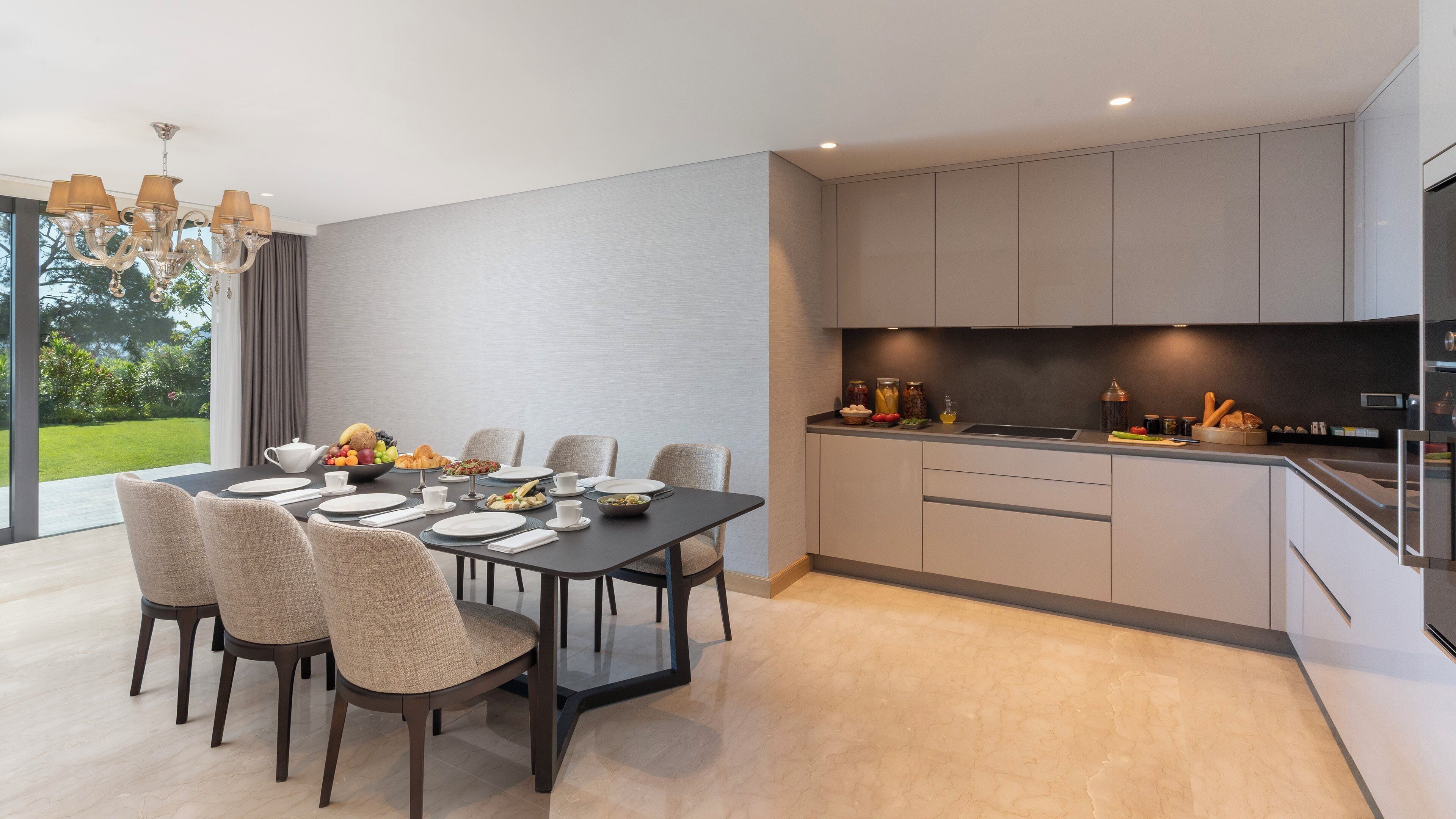 Una cocina moderna con comedor, que cuenta con un amplio ventanal, una araña y vistas al exterior.