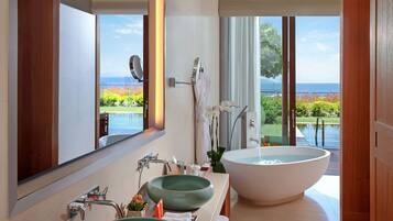 A modern bathroom with a large bathtub, two sinks, and a view of the ocean.