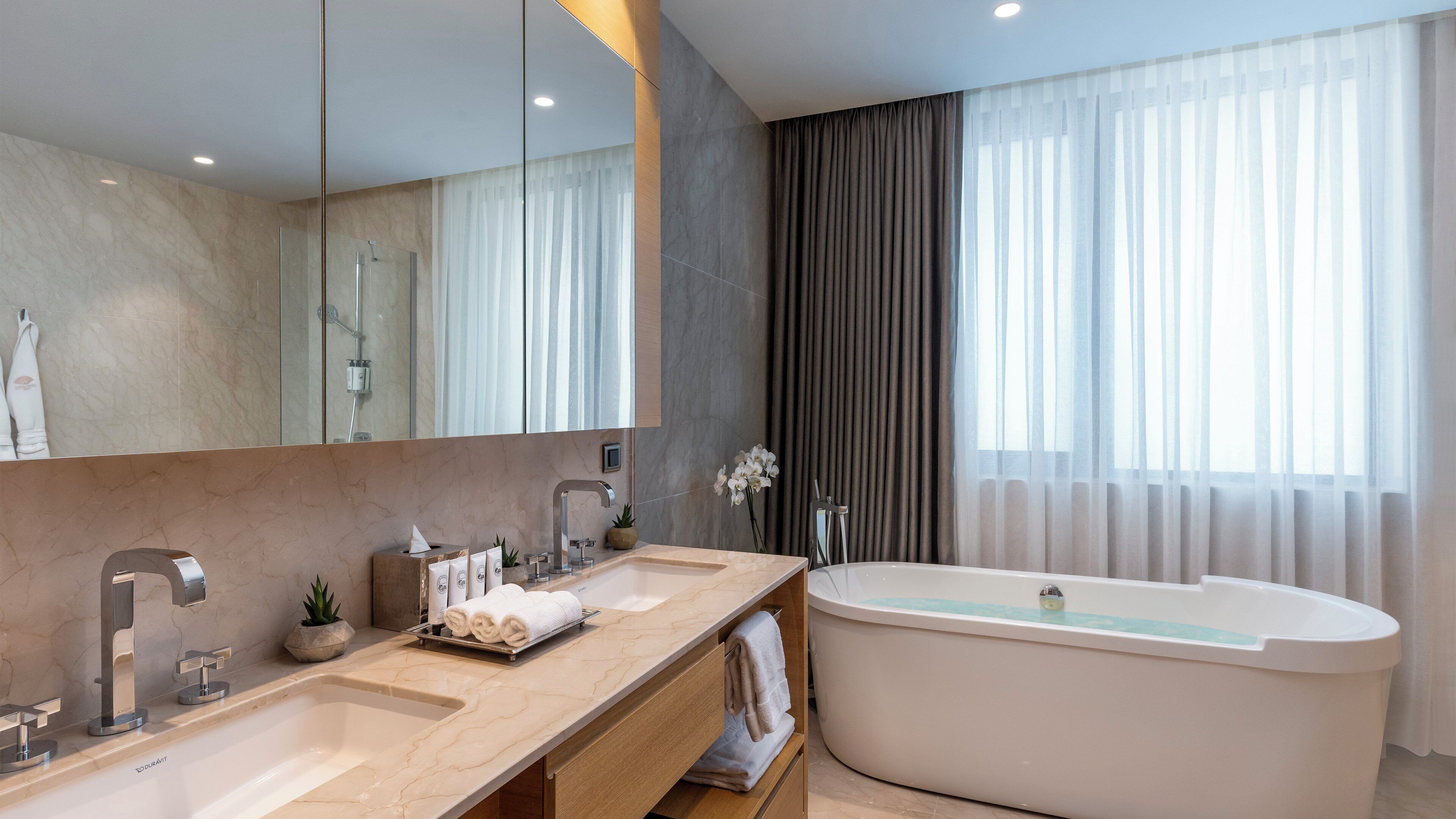 Une salle de bain moderne avec une grande baignoire, un meuble-lavabo à deux vasques et un grand miroir.
