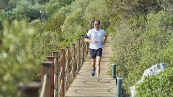 Una persona trotando sobre una pasarela de madera rodeada de follaje.