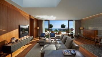 Una sala de estar moderna con un televisor grande, asientos cómodos, una mesa de centro y vistas al mar.
