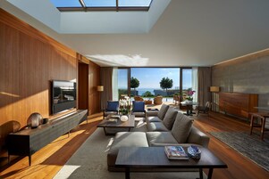 Una sala de estar moderna con un televisor grande, asientos cómodos, una mesa de centro y vistas al mar.